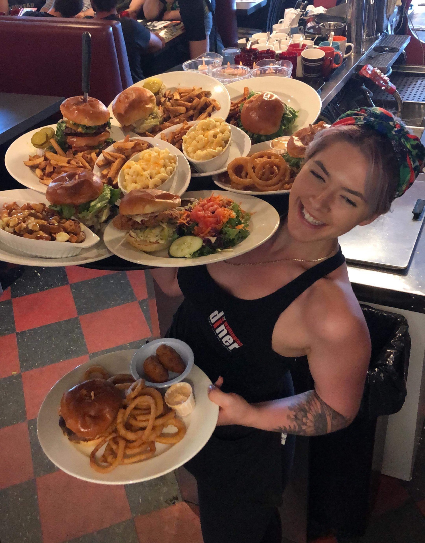 A Wellington Diner server with burgers, mac, poutine, and onion rings.